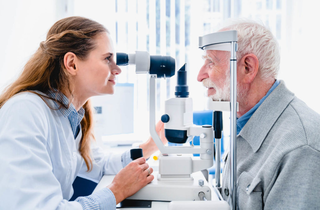 An optometrist examining the eyes of an older adult man.