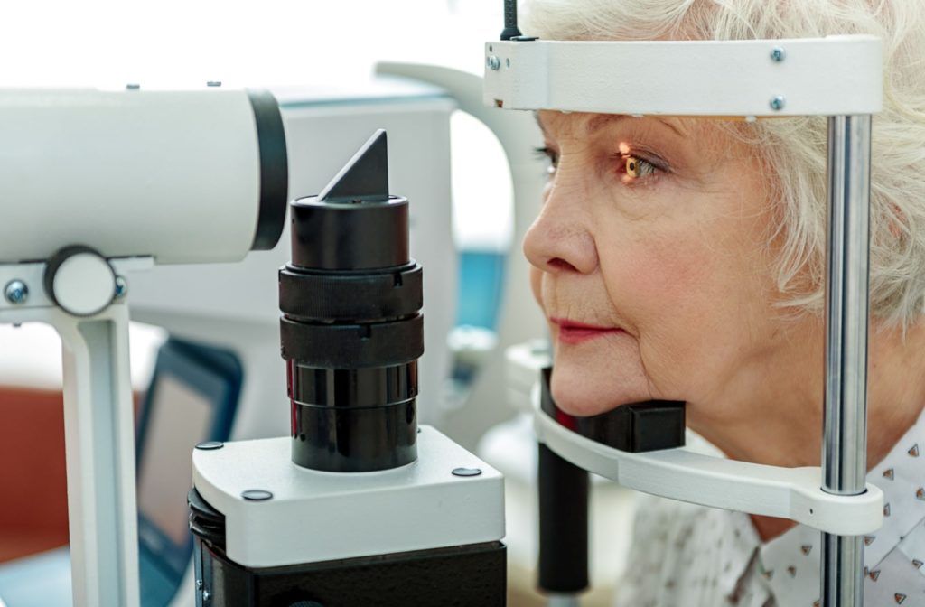 An older adult woman undergoing a slit lamp examination as a part of her eye exam.