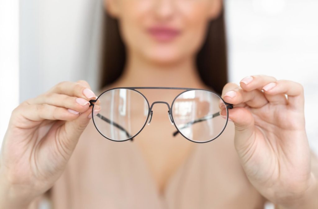 A woman holding a pair of glasses with myopia control lenses.