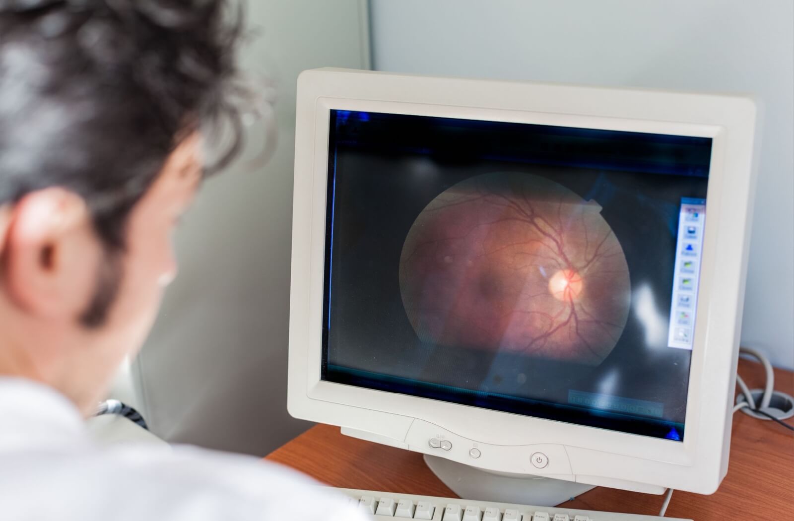 An optometrist looking at the results of a patient's OTC scan on a computer.