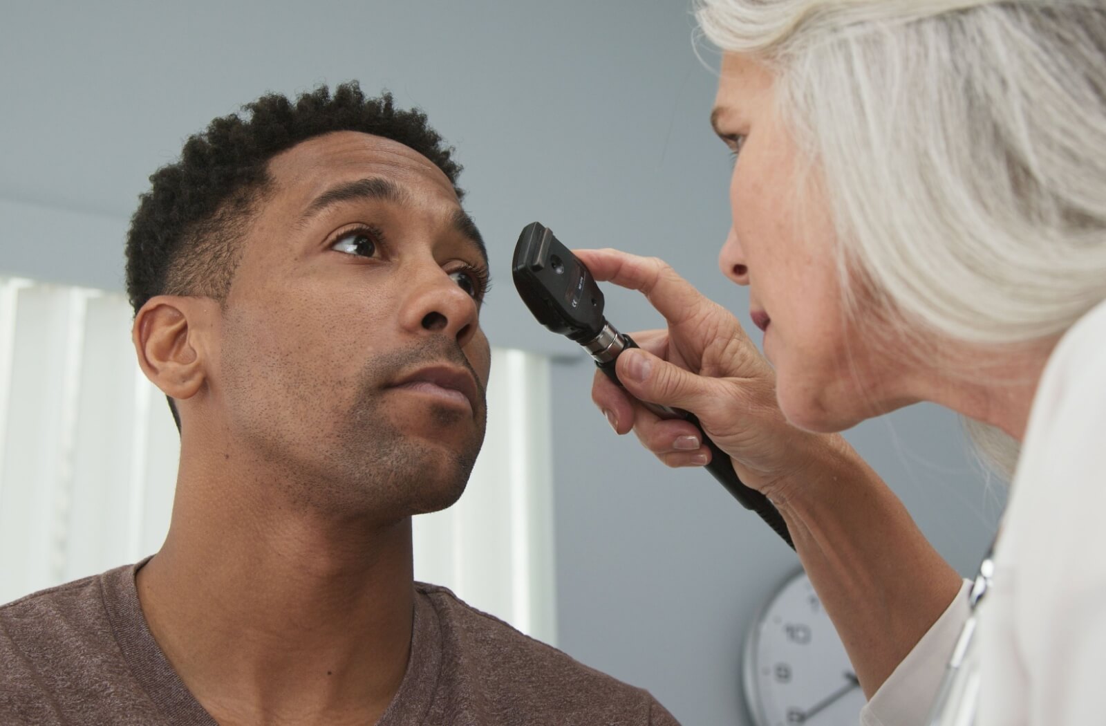 A male patient has his eyes checked by an optometrist as part of an eye exam.