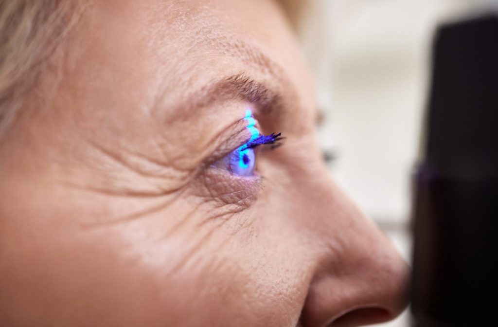 A close-up view of a light shining in a senior woman's right eye during an eye exam.