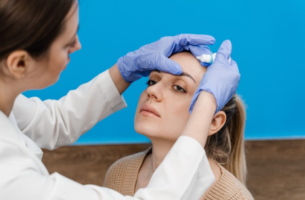 An optometrist places prescription eye drops into her patient's eye to treat dry eye syndrome.
