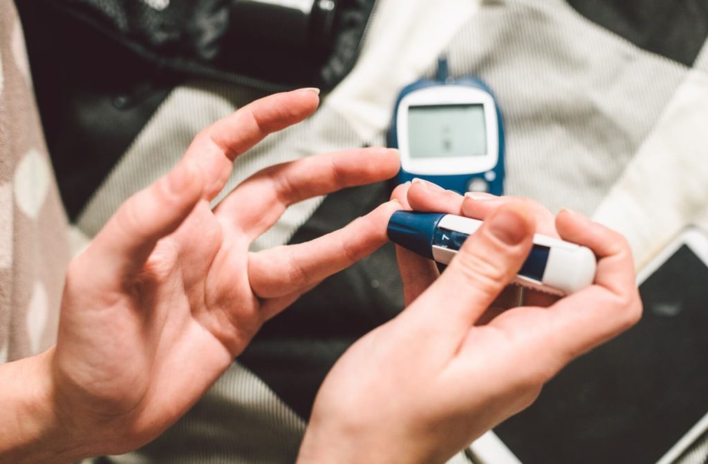 Close-up of a person's hands as they use a tester to measure their blood sugar levels & manage diabetes.