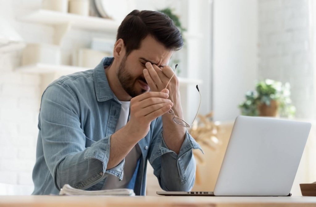 A person rubbing their eyes due to eye strain symptoms.