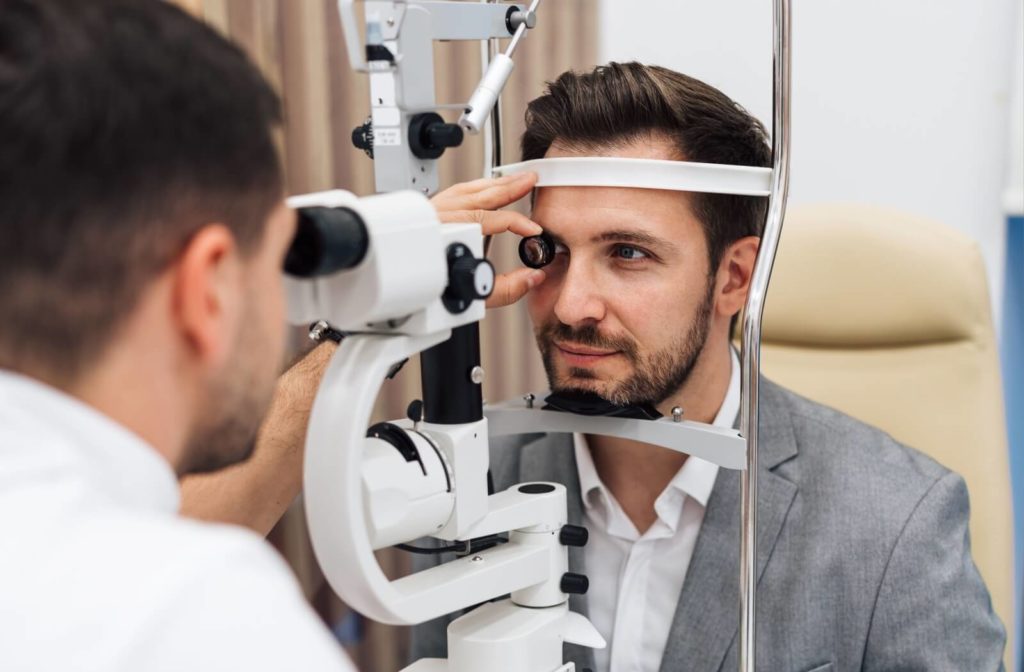 An adult receiving a comprehensive eye exam from an optometrist in a bright, modern clinical setting