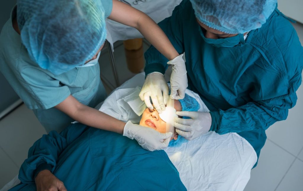 An ophthalmologist places a covering over their patient's eye after finishing cataract surgery on their eye.