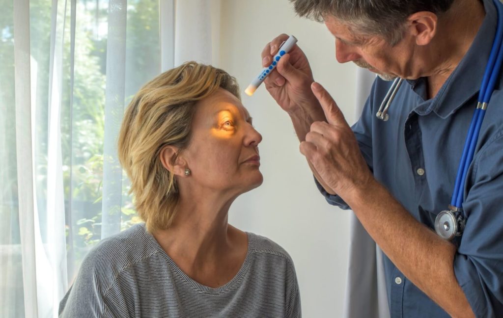 An ophthalmologist uses a light to inspect a patient's eye in between cataract surgeries to asses the eye's healing.