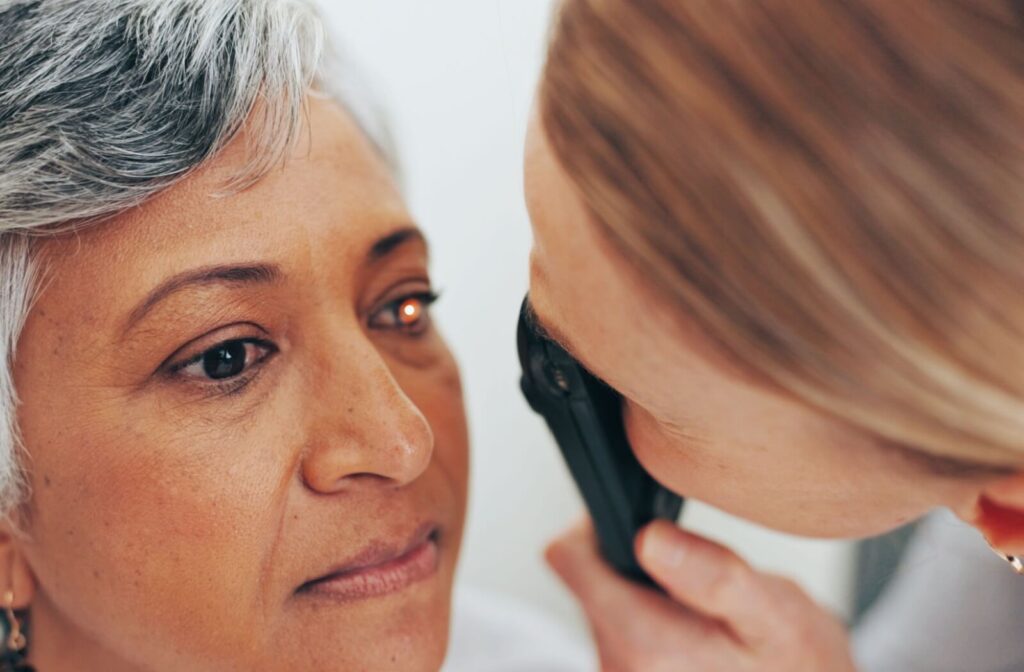An optometrist carefully checking an older patient's eyes to look for signs of retinal damage and floaters.