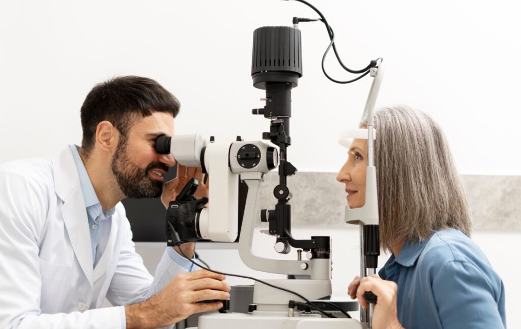 An adult sits in front of a slit lamp while their optometrist carefully examines their retinas for signs of eye conditions.