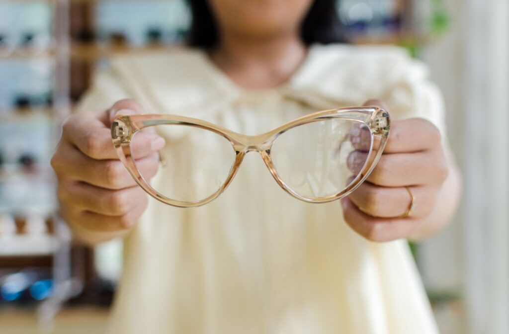 A person holding out a pair of gold translucent glasses.