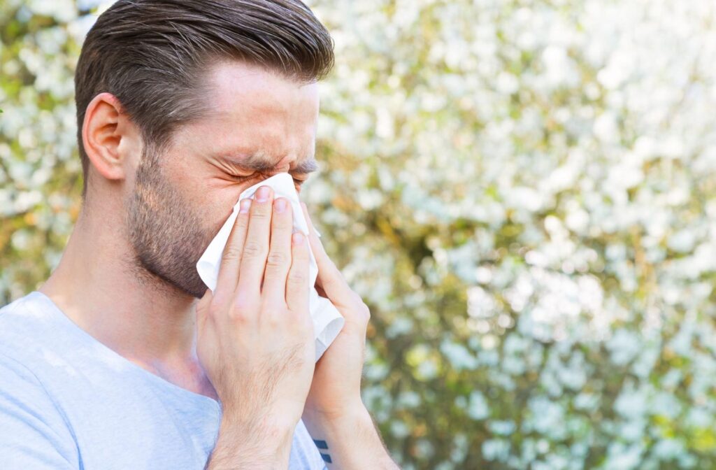 A person blowing their nose into a tissue due to their spring allergies.