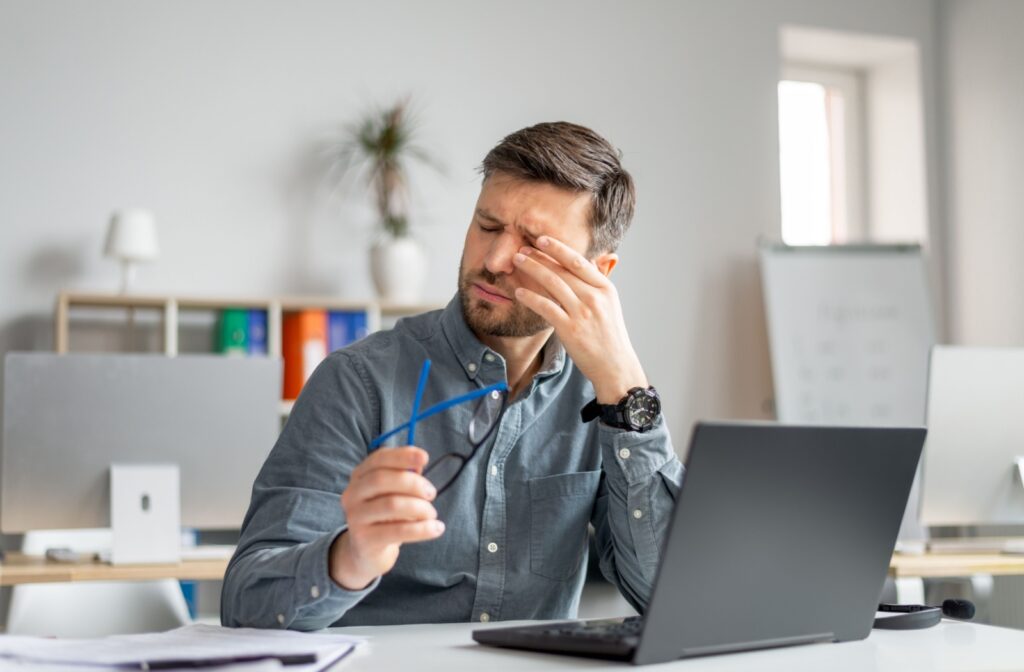A person removing their glasses to rub at their irritated eyelid.