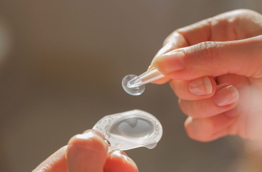 A fresh contact lens package with a person using contact lens tweezers to remove the contact lens from the package