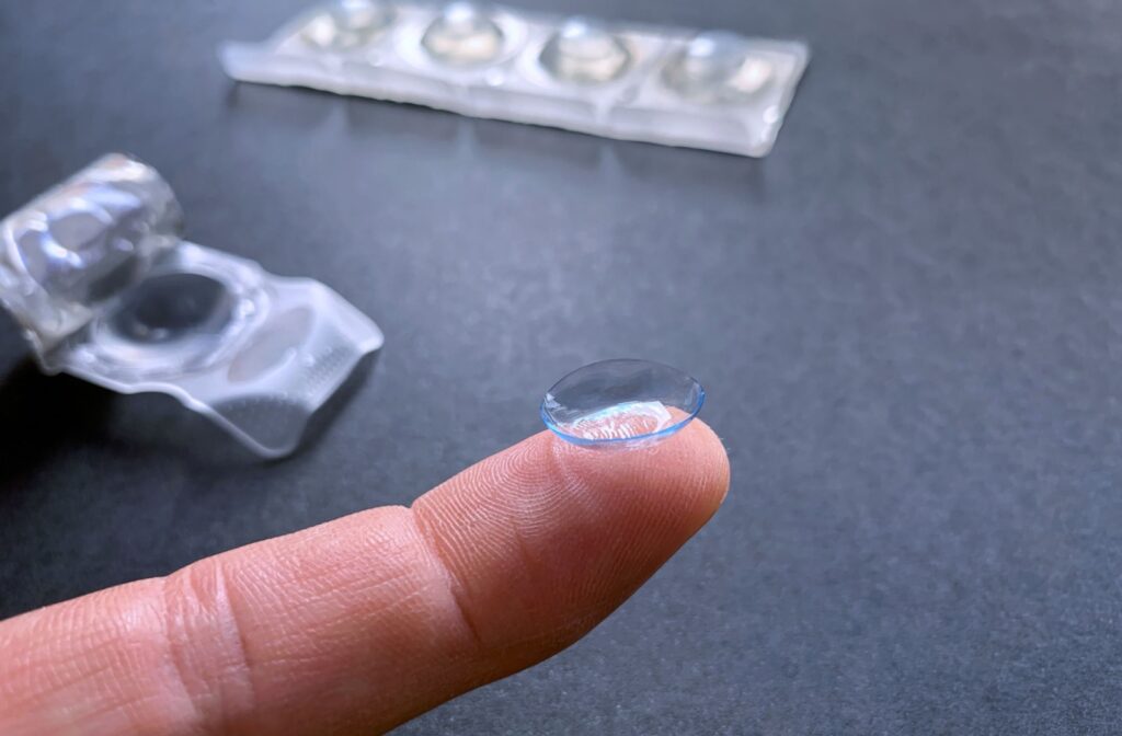 A contact lens resting on the tip of a persons finger fresh out of the package